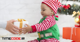 دانلود عکس استوک : کادو کریسمس به نوزاد Adorable Baby Boy In Elf Costume Getting Christmas Gift
