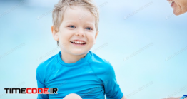 دانلود عکس استوک : پسر بچه در حال خنده Cute Little Boy Talking To Mom On The Beach And Smiling