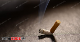 دانلود عکس استوک : سیگار له شده Lit Cigarette Butt With Smoke On The Ground