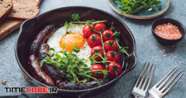 دانلود عکس نیمرو  Fried Egg With Sausages And Cherry Tomatoes In A Black Iron Pan