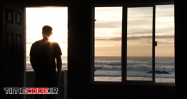 دانلود فوتیج ضد نور مرد پشت پنجره در حال تماشا دریا Person Watching Ocean Sunset
