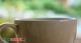دانلود فوتیج فنجان با بخار چای Close Up Of Steaming Tea Cup On The Blurred Green.