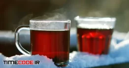 دانلود فوتیج دو لیوان چای داغ با بخار در زمستان Steaming Tea In A Glass Standing On Snow At Tree Branch