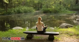 دانلود فوتیج تمرین یوگا در طبیعت Woman Doing Yoga Sitting On A Bench In The Woods