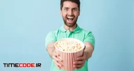 دانلود عکس مرد با پاپ کورن Portrait Of A Handsome Bearded Man Eating Popcorn While Watching Movie