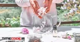 دانلود عکس زن در حال جمع کردن گلبرگ رز در گلدان Woman Preparing Roses Water With Pink Rose Petals In Glass Bowl.